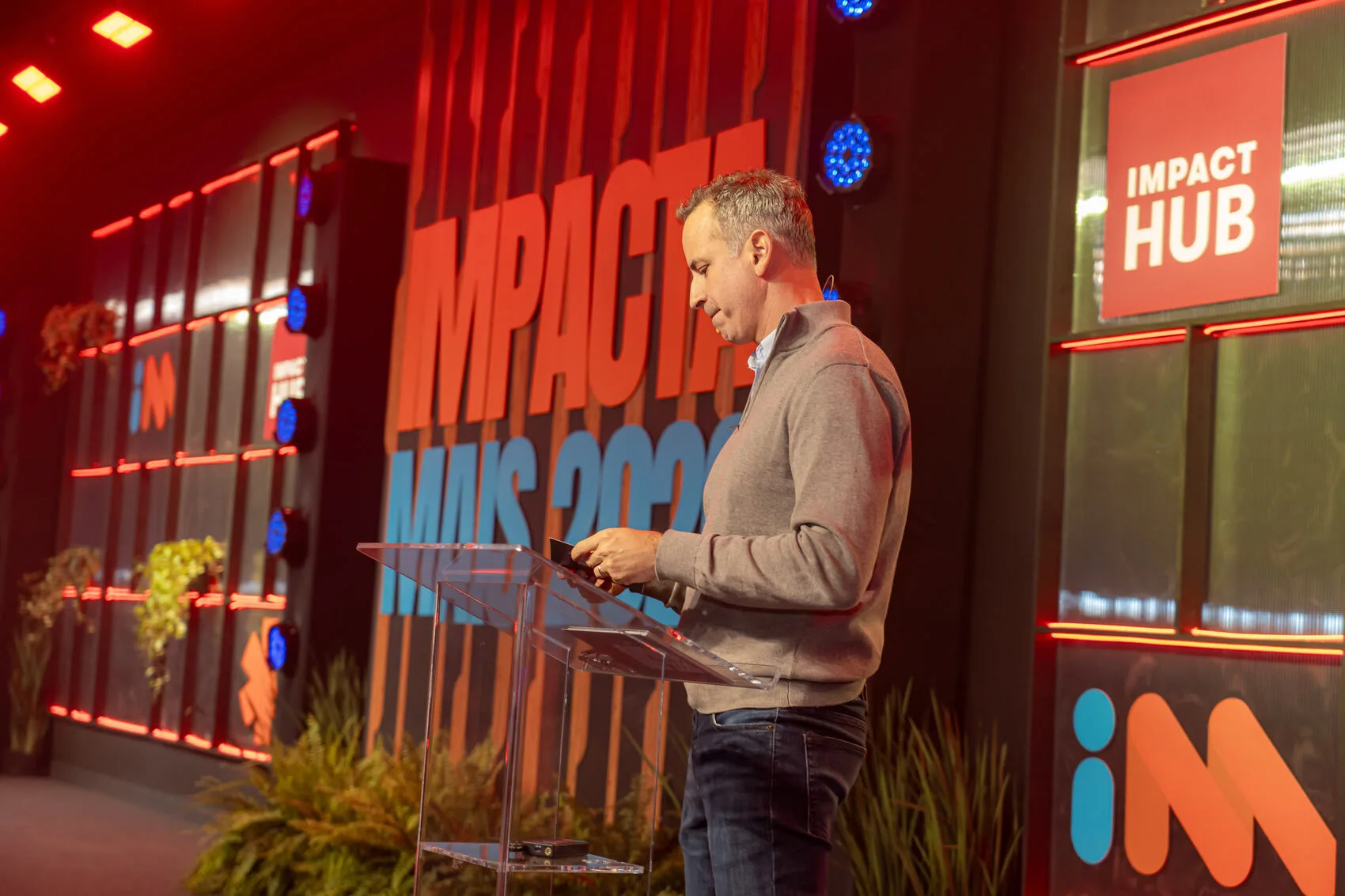 Liderança do Impact Hub no palco do Impacta Mais, evento do ecossistema de impacto, com a marca Impact Hub em destaque